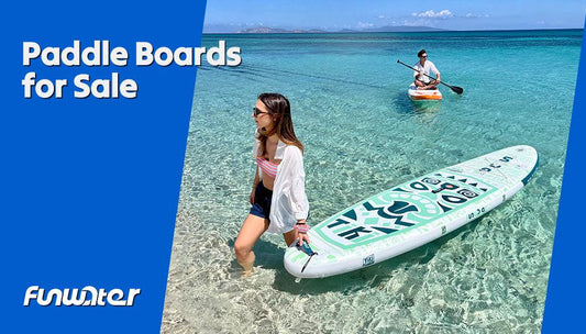 This image shows a woman walking in clear, shallow ocean water, carrying a FunWater paddle board. Another person is paddling on a board in the background. The text reads, "Paddle Boards for Sale."